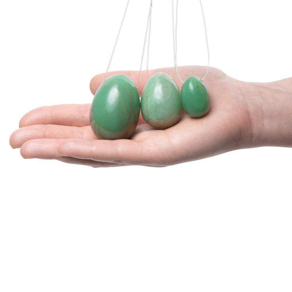 La Gemmes jade yoni egg set featuring three smooth, natural stones in varying sizes on a soft surface.